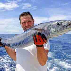 Deep sea fishing. Fisherman holding a wahoo fish